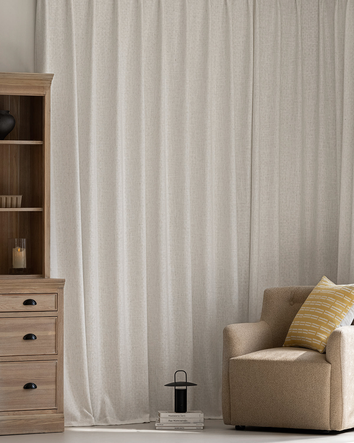 The Alma linen texture drapes serving as a neutral backdrop for a wood cabinet and armchair.