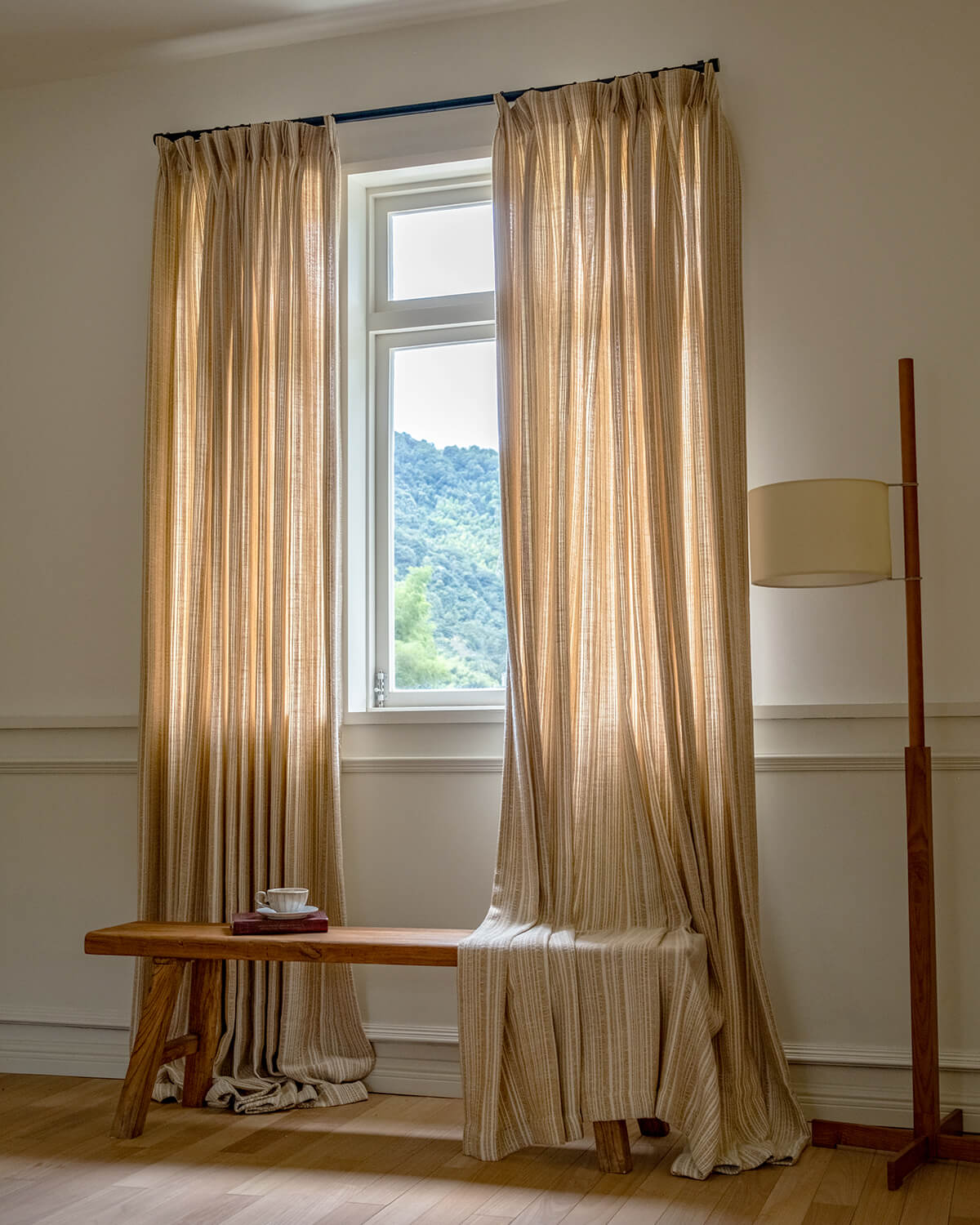 The heavyweight, well-draped fabric of the Thea striped curtain shown over a wooden bench.