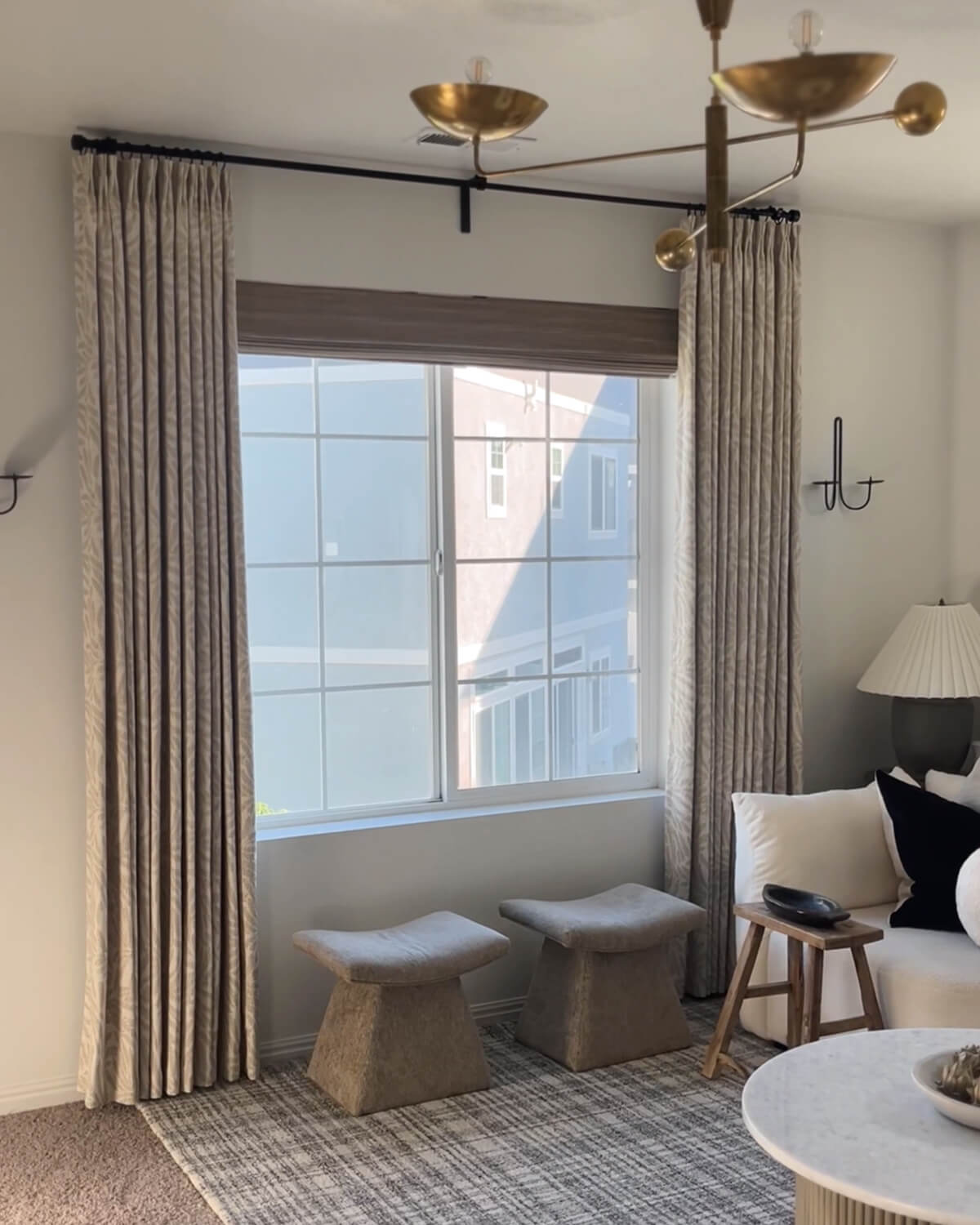 A pair of Mila leaf pattern pinch pleated drapes framing a window in a modern living room.