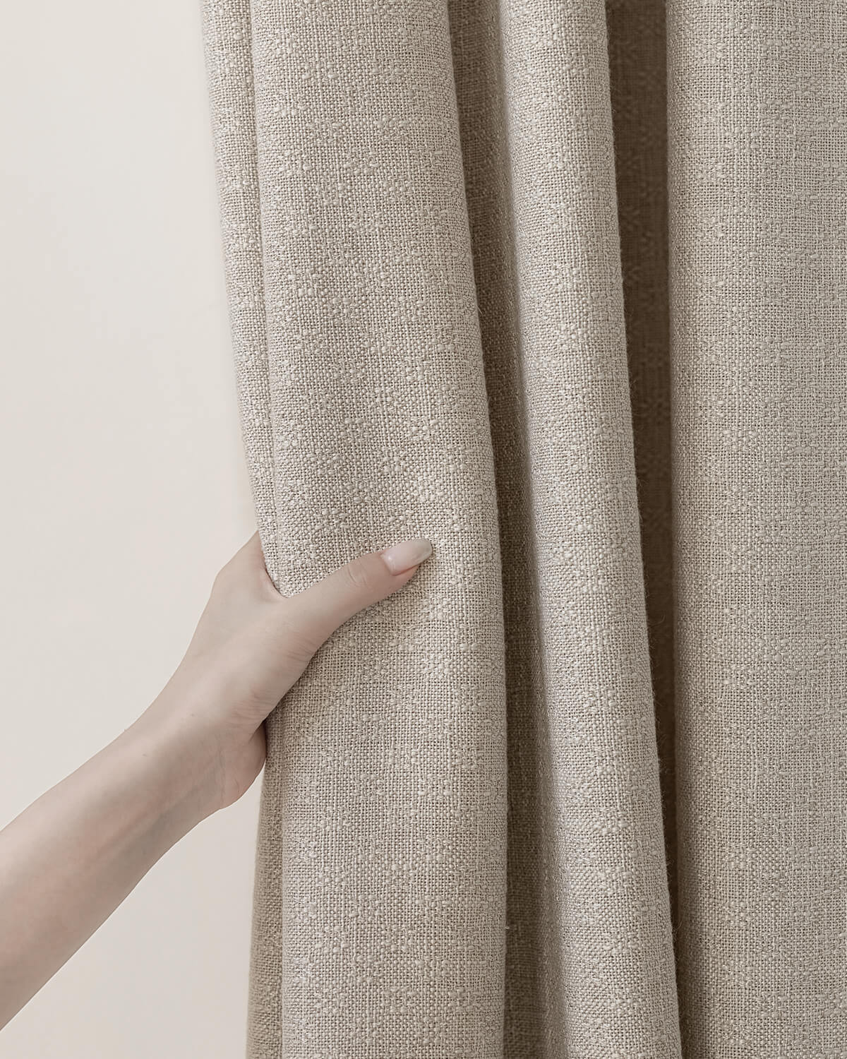 A hand holding the thick Alma linen blend drape to show its subtle woven pattern.