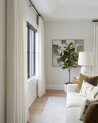 A cozy corner featuring Luma herringbone curtains on two windows, paired with a white sofa and armchair.