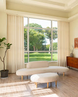 A spacious, modern living room featuring floor-to-ceiling Tina thick linen blend curtains and a curved white sofa.