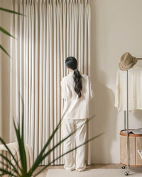 A woman standing by the floor-length Kely Chenille curtains, demonstrating their thick and luxurious feel.