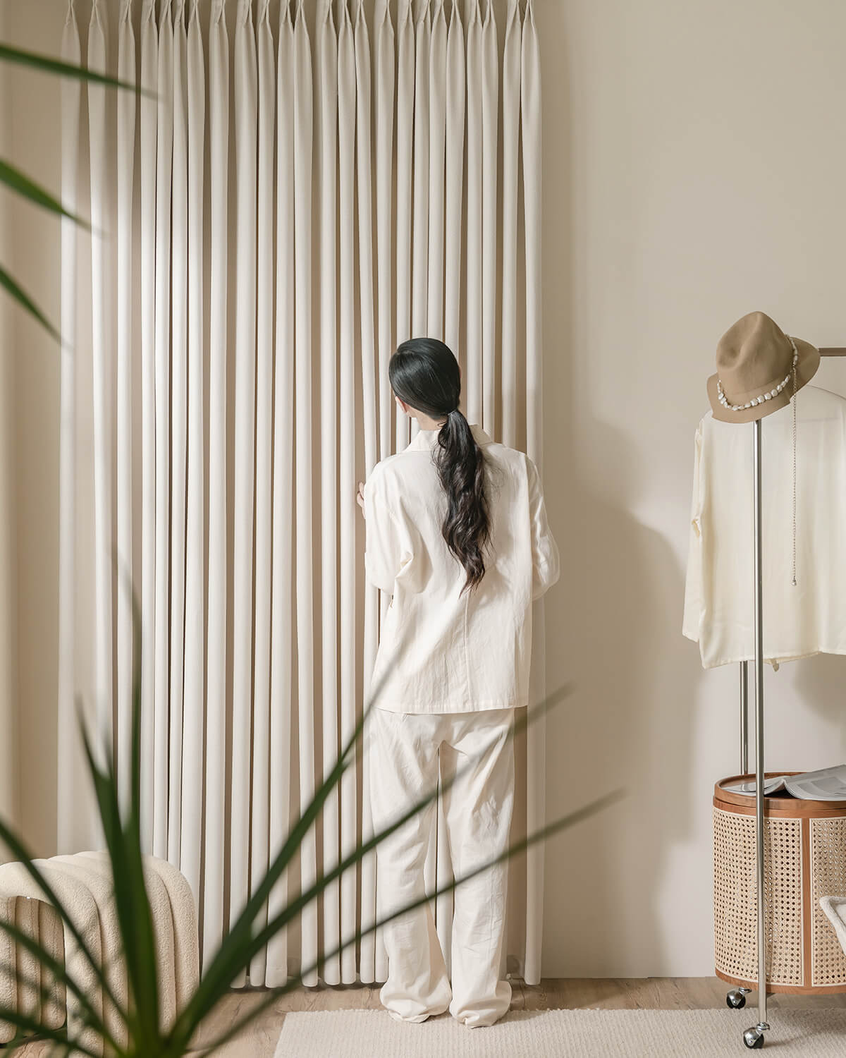 A woman standing by the floor-length Kely Chenille curtains, demonstrating their thick and luxurious feel.
