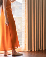 Lower section of puddle-length waffle drapes showing heavy fabric drape and ruffle trim next to a woman standing.