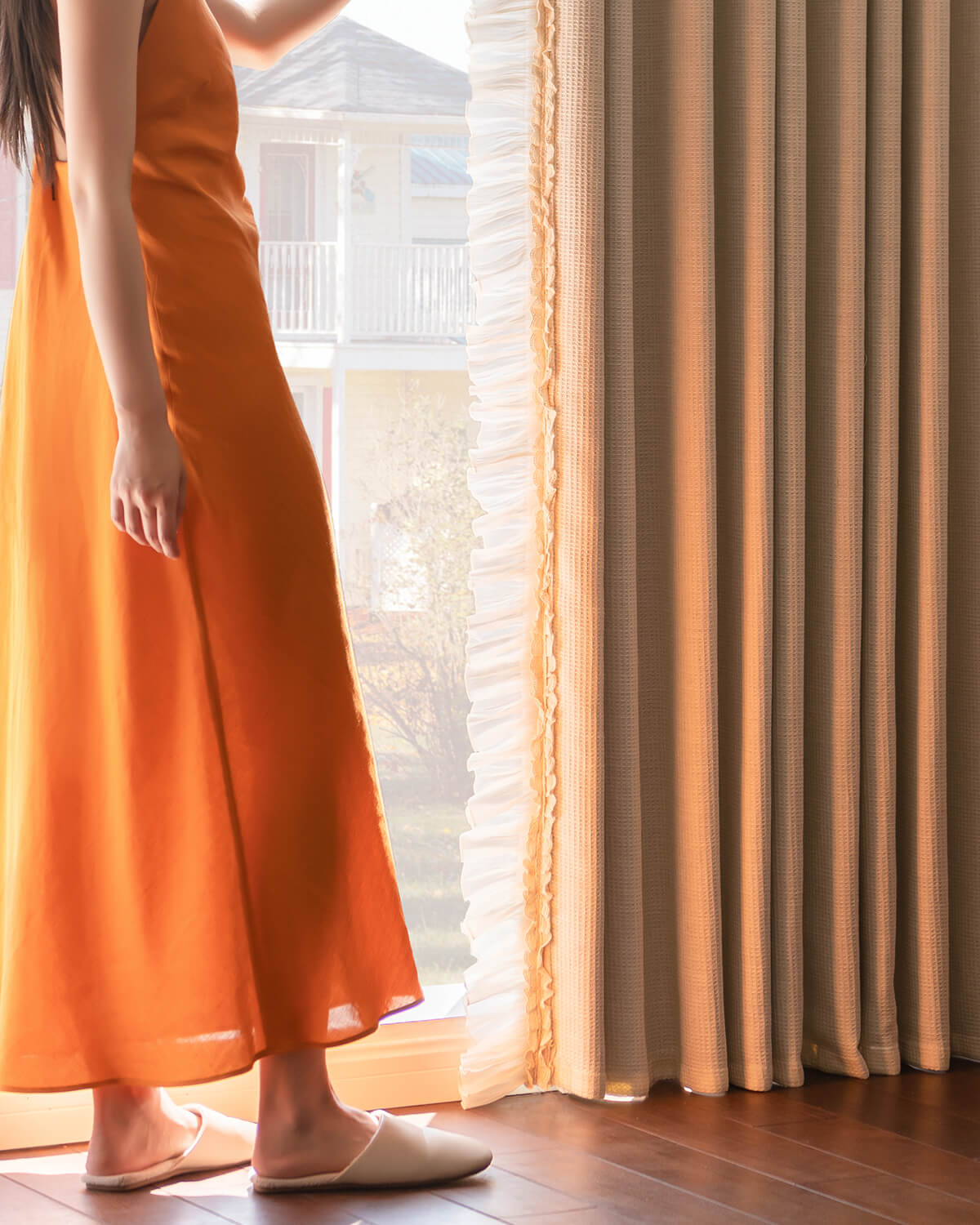 Lower section of puddle-length waffle drapes showing heavy fabric drape and ruffle trim next to a woman standing.