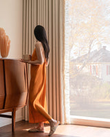 Lifestyle shot of a woman holding a cup next to heavy thermal waffle curtains featuring a unique ruffle side design.