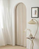 Kely Chenille pinch pleat curtains used to frame an arched doorway in a minimalist interior.