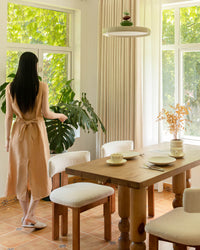 A dining room featuring Mell beige Chenille blackout curtains and white boucle chairs.