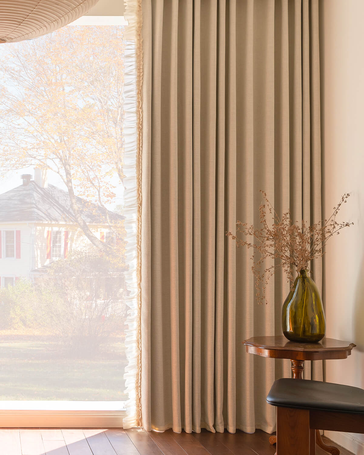 Side view of waffle textured drapes with ruffle edge filtering natural light, creating a warm atmosphere in the living room.