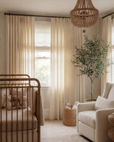 Pinch pleat Darcy Striped Beige Curtains in a stylish nursery with a brass crib and beaded chandelier.