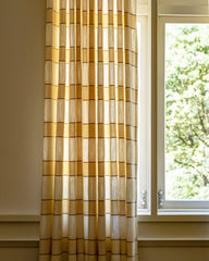 A pair of Ivy woven striped curtains filtering light while framing a tall window.