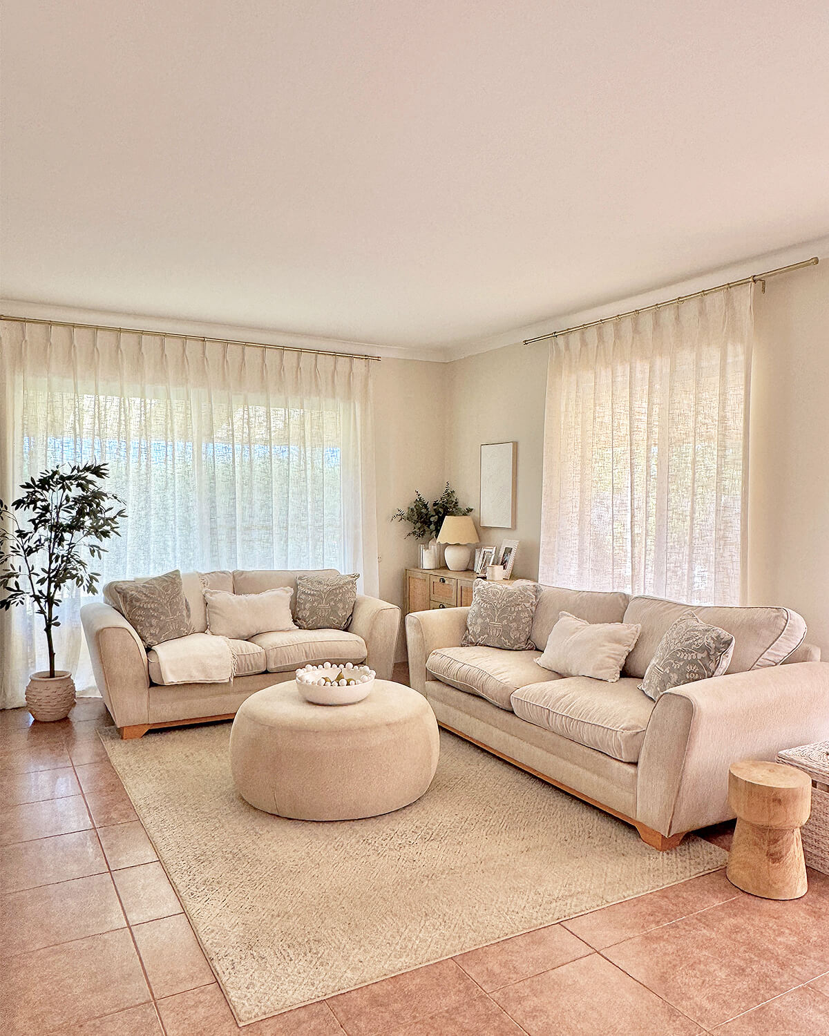 Liz pinch pleated linen blend curtains framing a large window in a cozy, sunlit living area.