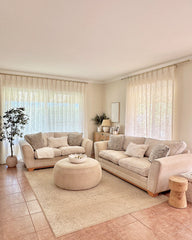 Liz pinch pleated linen blend curtains framing a large window in a cozy, sunlit living area.