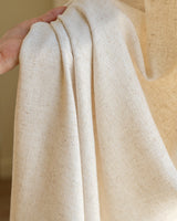 A hand holding the edge of the Tina curtain, highlighting its thick weight and premium linen blend quality.