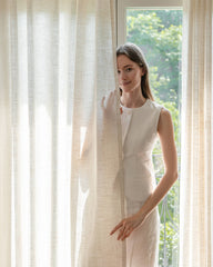 A woman peeking from behind the semi-sheer Liz linen textured curtain panel.