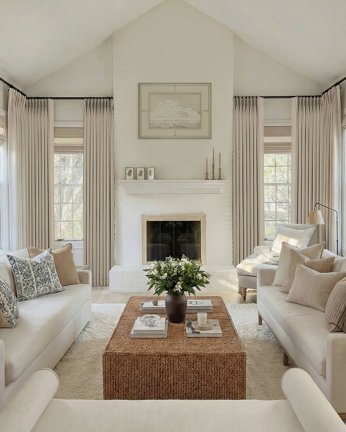 A wide view of a bright living room featuring heavy Vivi Chenille pinch pleated curtains framing multiple windows near a fireplace.